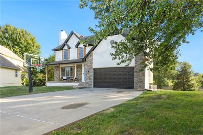 View of front of home featuring a front yard, a garage, covered porch, and central AC unit | Image 1