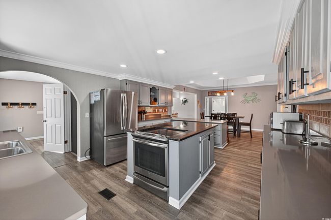 Kitchen with appliances with stainless steel finishes, a center island, crown molding, dark countertops, and gray cabinets | Image 35