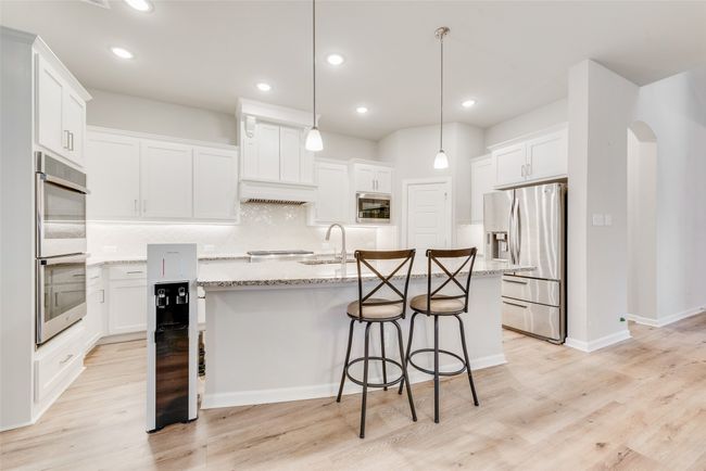 Kitchen with a sink, stainless steel appliances, tasteful backsplash, a breakfast bar, and an island with sink | Image 9