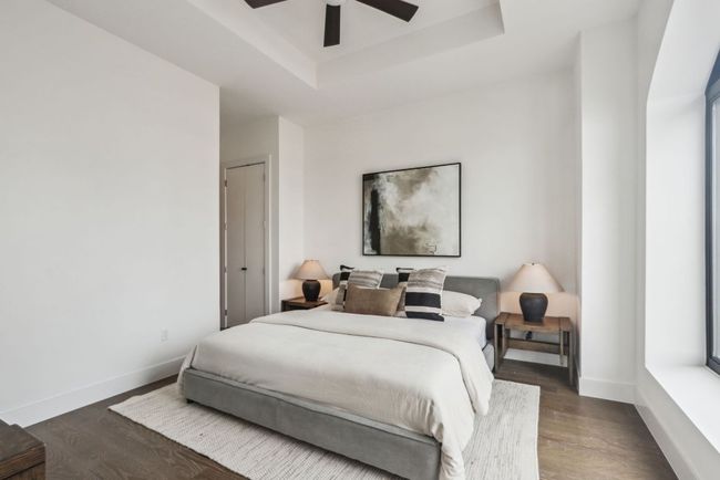 Bedroom with baseboards, a raised ceiling, ceiling fan, and wood finished floors | Image 12