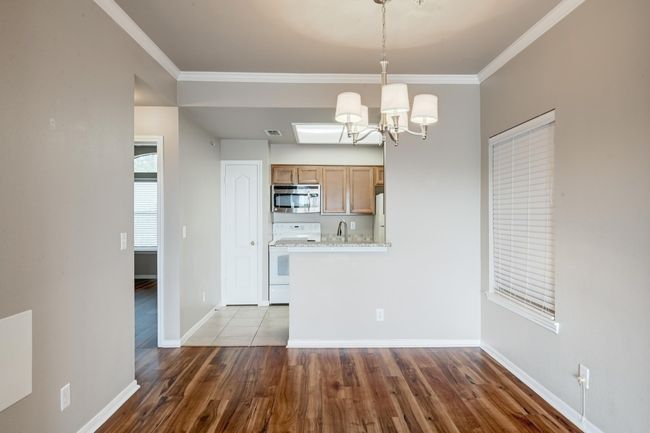 Kitchen with stainless steel microwave, white range with electric stovetop, a chandelier, crown molding, and wood finished floors | Image 12