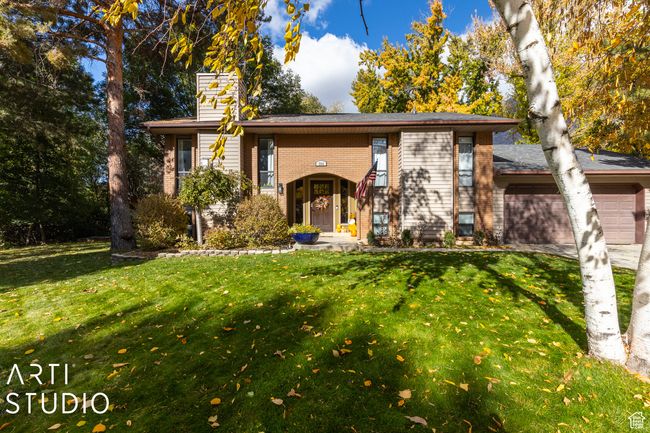 View of front of house with an attached garage, a front lawn, a chimney, brick siding, and driveway | Image 4