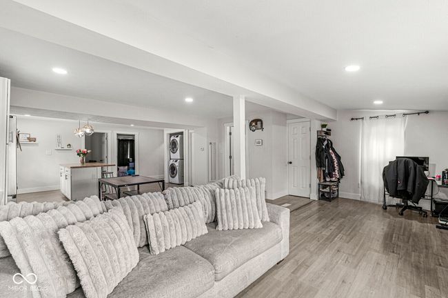 living room with stacked washer and clothes dryer, recessed lighting, light wood finished floors, and baseboards | Image 6