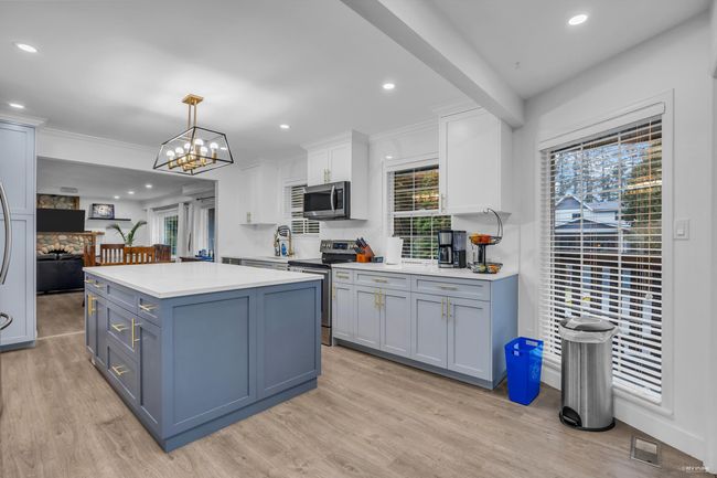 Kitchen featuring appliances with stainless steel finishes, light countertops, light wood-style floors, a center island, and white cabinetry | Image 10
