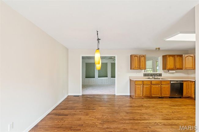 Kitchen featuring dishwasher, light countertops, light wood-type flooring, baseboards, and brown cabinetry | Image 6