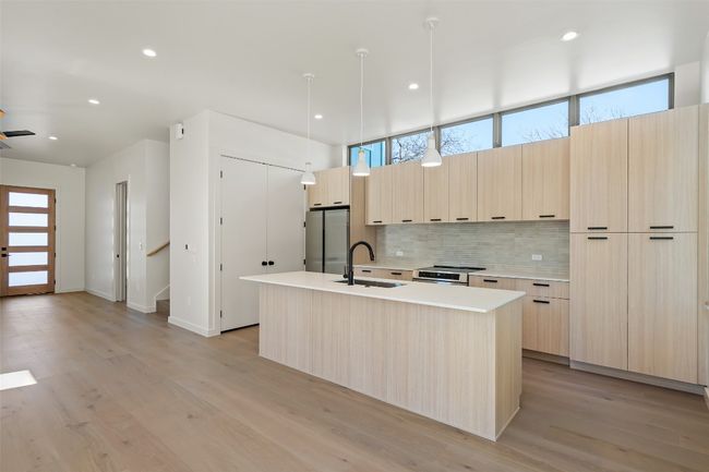 Kitchen with light brown cabinets, stainless steel appliances, a sink, backsplash, and modern cabinets | Image 4