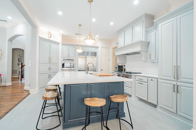 Kitchen featuring arched walkways, crown molding, stainless steel appliances, and light countertops | Image 11