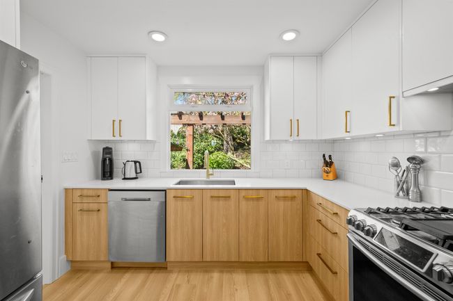 Kitchen with light wood finished floors, stainless steel appliances, light countertops, modern cabinets, and a sink | Image 9