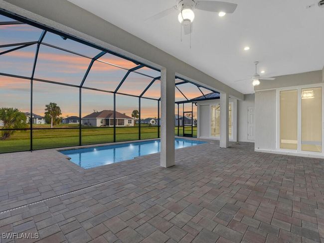 Pool at dusk with an outdoor pool, ceiling fan, a patio, and a lawn | Image 6