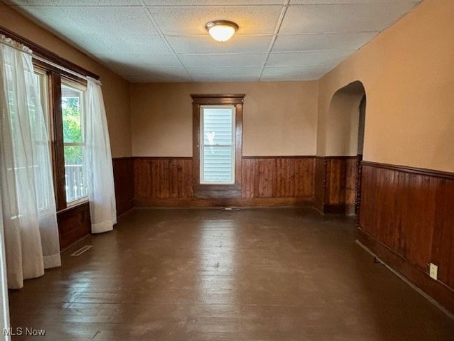 Unfurnished room featuring a drop ceiling, wood walls, and dark hardwood / wood-style flooring | Image 5