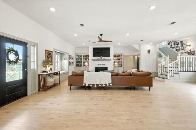 Living room featuring light wood-style flooring, a large fireplace, stairway, recessed lighting, and a ceiling fan | Image 18