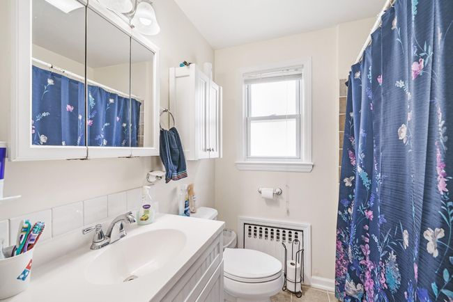 Bathroom with radiator, toilet, a shower with curtain, and vanity | Image 18