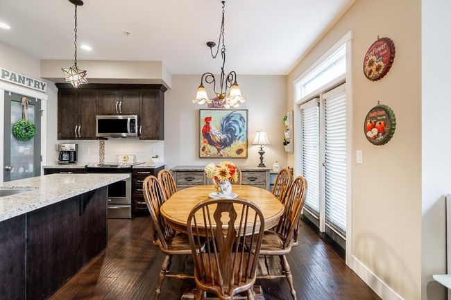 Dining area with dark wood finished floors, recessed lighting, baseboards, and a chandelier | Image 10