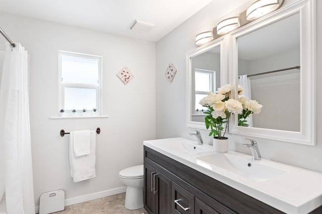 Bathroom with toilet, double vanity, baseboards, and curtained shower | Image 20