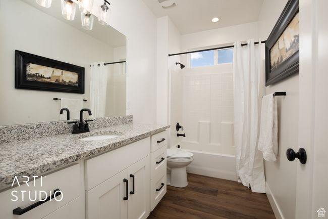 Full bathroom with vanity, toilet, hardwood / wood-style floors, and shower / bath combo | Image 25