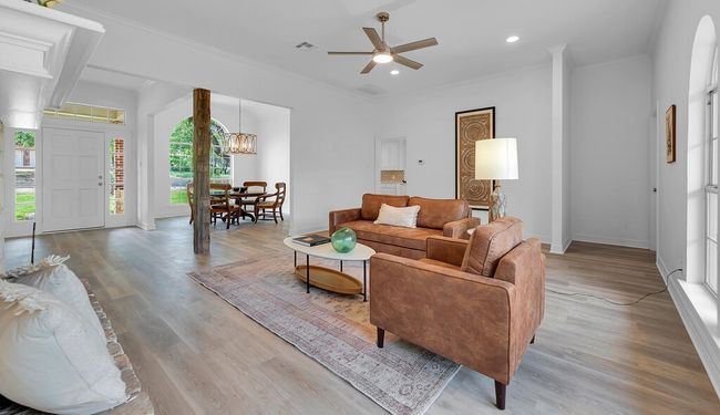 Living area with baseboards, visible vents, ceiling fan with notable chandelier, wood finished floors, and ornamental molding | Image 10