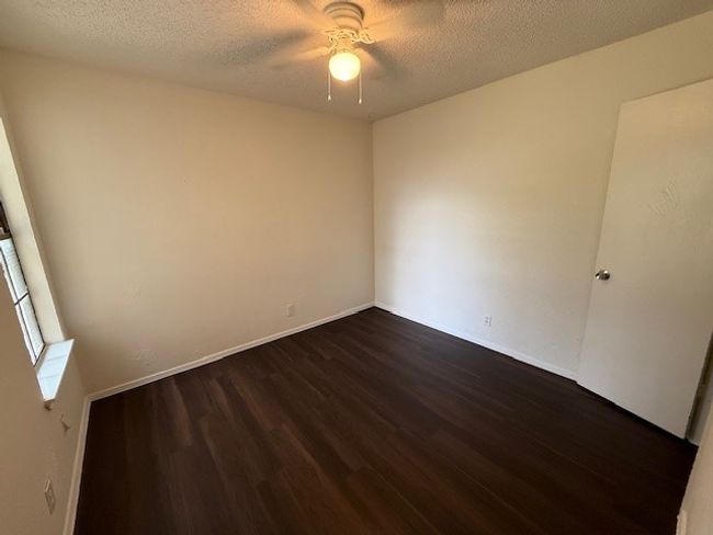 Unfurnished room featuring dark wood-style flooring, ceiling fan, a textured ceiling, and baseboards | Image 9