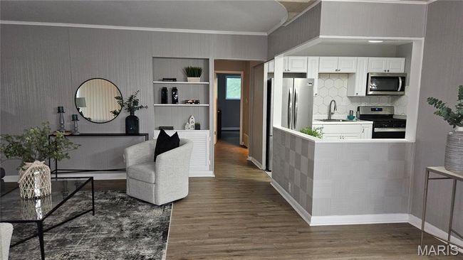 Kitchen with stainless steel appliances, crown molding, dark wood-style floors, white cabinetry, and backsplash | Image 4