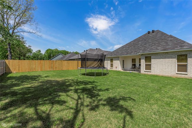 View of yard featuring a patio, a trampoline, and a fenced backyard | Image 27