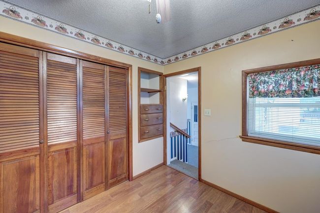 Hall featuring a textured ceiling, light wood-style floors, baseboards, and an upstairs landing | Image 9