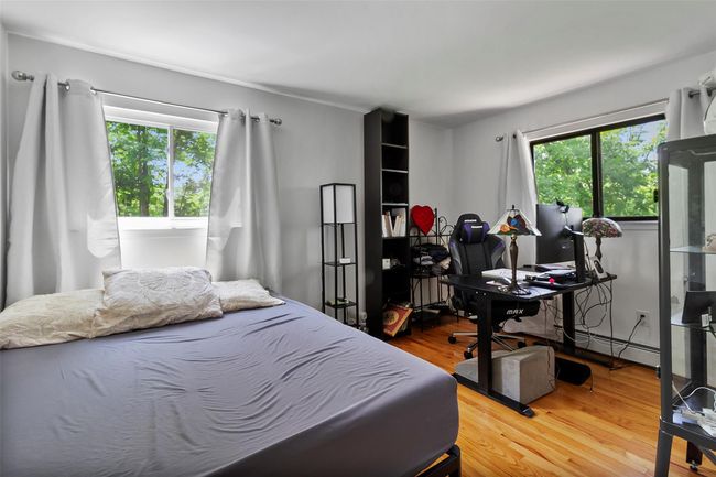 Bedroom featuring wood finished floors, a desk, and a baseboard heating unit | Image 10