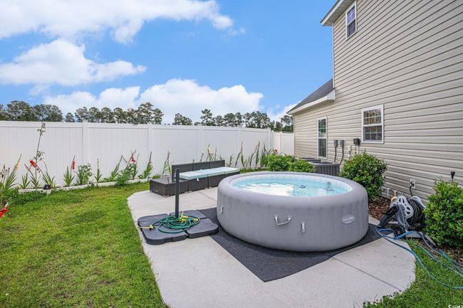 Fenced backyard with a hot tub, a patio area, and an outdoor living space | Image 24