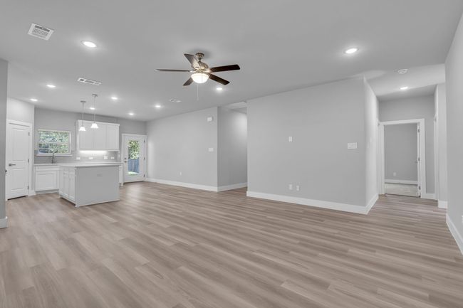 Unfurnished living room featuring visible vents, light wood finished floors, baseboards, ceiling fan, and recessed lighting | Image 7