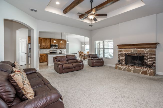 Living room with light carpet, recessed lighting, ceiling fan, a raised ceiling, and a fireplace | Image 11