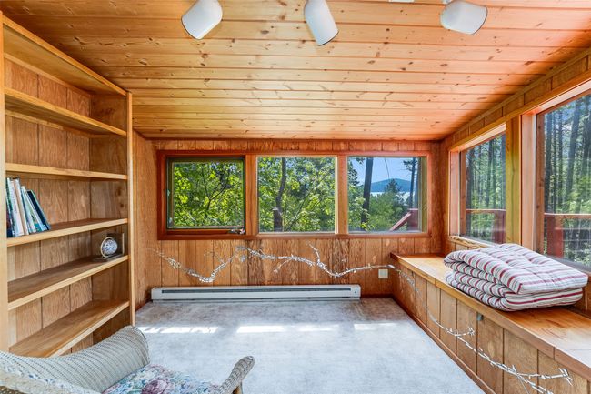 Living area featuring a baseboard radiator, healthy amount of natural light, wooden ceiling, carpet floors, and wooden walls | Image 14