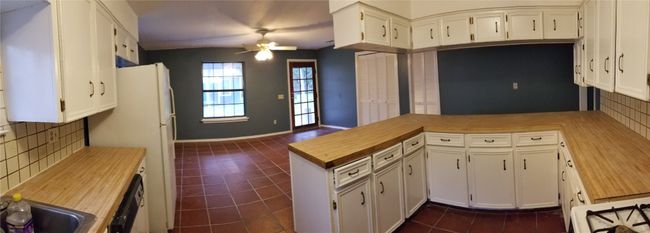 Kitchen with a peninsula, ceiling fan, backsplash, and dark tile patterned flooring | Image 16