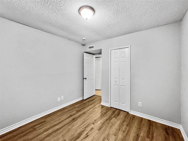 Unfurnished bedroom featuring wood finished floors, a textured ceiling, and a closet | Image 10