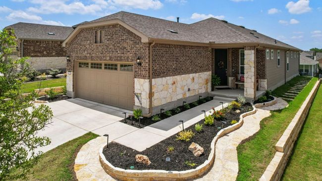 View of front of home with an attached garage, a shingled roof, brick siding, and stone siding | Image 37