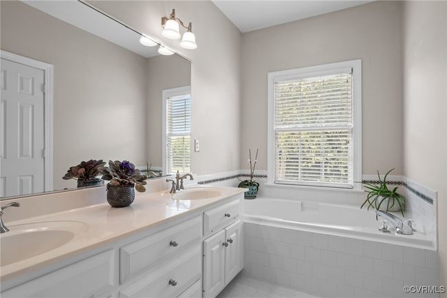 First floor primary bathroom with tub and double vanity | Image 15