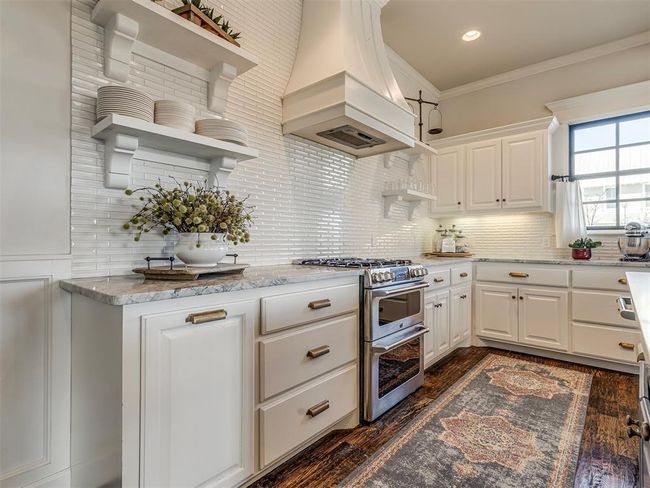 Kitchen featuring range with two ovens, dark wood-style flooring, custom exhaust hood, open shelves, and crown molding | Image 9
