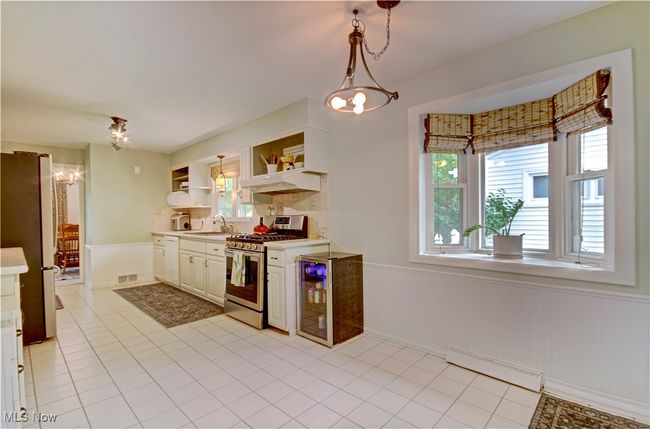 Kitchen with a baseboard heating unit, appliances with stainless steel finishes, a chandelier, wainscoting, and open shelves | Image 18