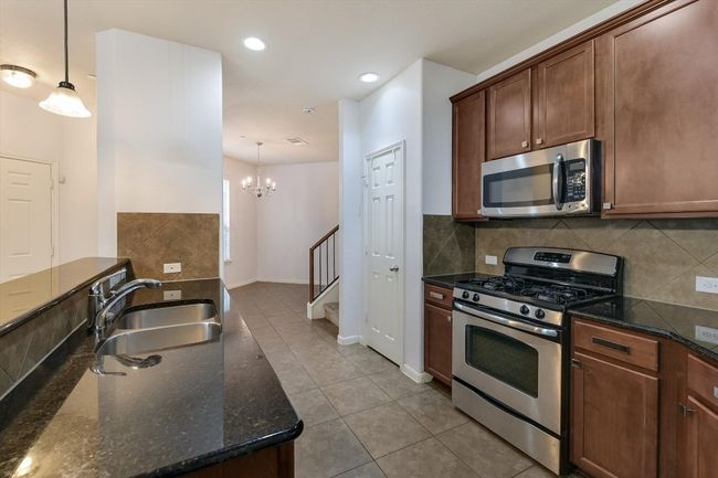 Kitchen with stainless steel appliances, tile patterned floors, dark stone counters, decorative backsplash, and recessed lighting | Image 10