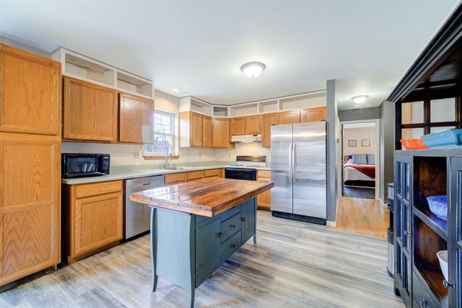 Kitchen with ample counters, appliances with stainless steel finishes, a sink, and light wood-style floors | Image 11