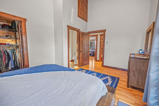 Bedroom featuring baseboards, radiator, a towering ceiling, light wood-type flooring, and a closet | Image 28