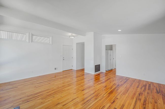 Living room with light wood-style flooring, lofted ceiling, and visible vents | Image 5