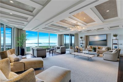 Living room featuring floor to ceiling windows, a chandelier, and a water view | Image 1