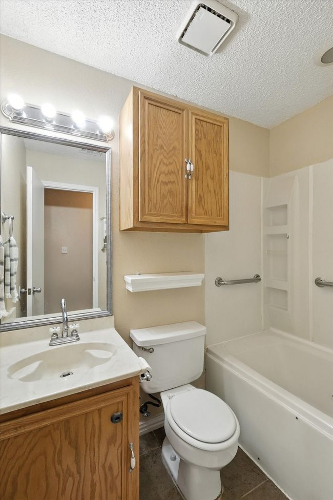 Bathroom featuring vanity, a textured ceiling, tile patterned flooring, and shower / tub combination | Image 14
