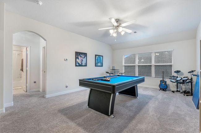 This spacious game room features, plush carpeting, and large windows for natural light. It includes a ceiling fan and space for creating a versatile entertainment area. | Image 27