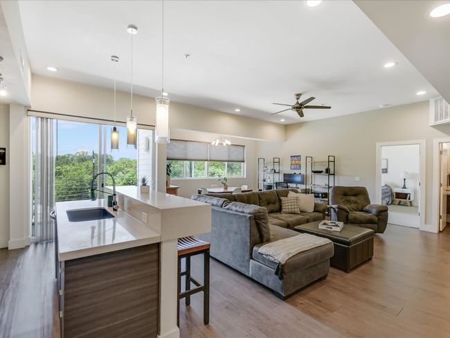 Living room with wood finished floors, recessed lighting, ceiling fan, and a chandelier | Image 10