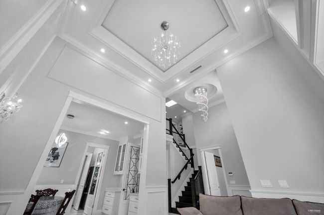 Staircase featuring a chandelier, a decorative wall, recessed lighting, a high ceiling, and crown molding | Image 7