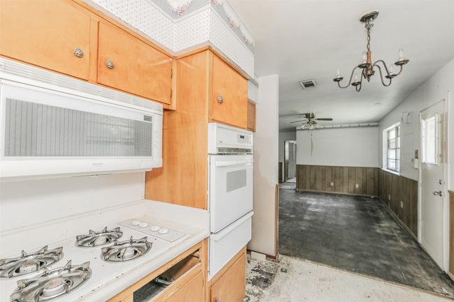 Kitchen featuring white appliances, a warming drawer, a wainscoted wall, a ceiling fan, and a chandelier | Image 9