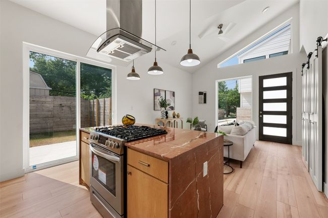 Kitchen with gas range, extractor fan, a kitchen island, light wood-style floors, and high vaulted ceiling | Image 11