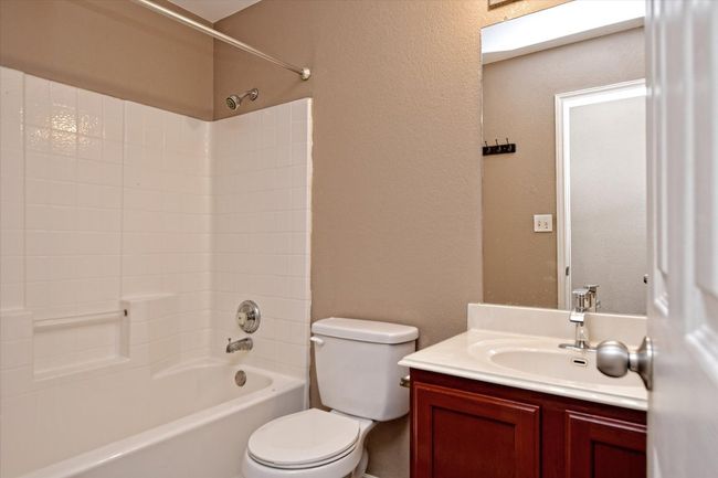 Full bathroom featuring toilet, washtub / shower combination, vanity, and a textured wall | Image 20