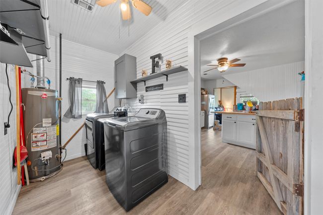 Laundry room featuring a ceiling fan, gas water heater, light wood-style flooring, laundry area, and washer and dryer | Image 17