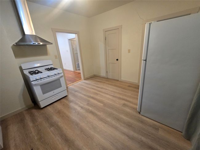 Kitchen with gas range gas stove, freestanding refrigerator, extractor fan, and wood finished floors | Image 22