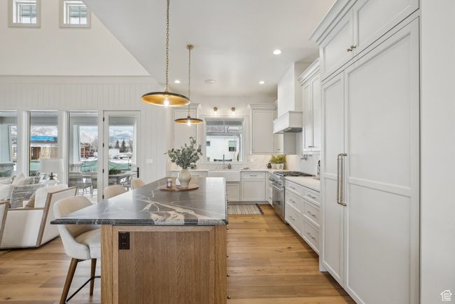 Kitchen featuring high end stove, a kitchen island, white cabinetry, and a kitchen breakfast bar | Image 12